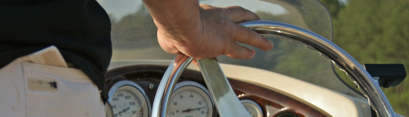 a man's hand on a boat steering wheel